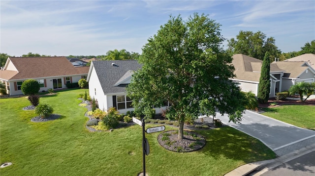view of front of home with driveway, roof with shingles, and a front yard