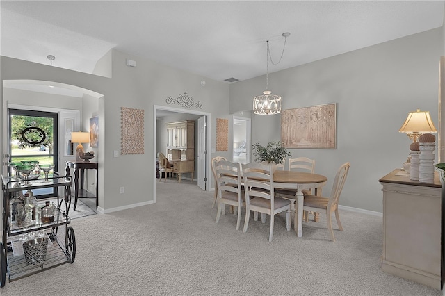 dining area featuring light colored carpet, arched walkways, and baseboards