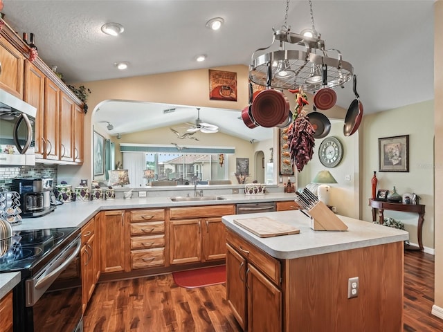 kitchen with dark wood finished floors, vaulted ceiling, stainless steel appliances, light countertops, and a sink