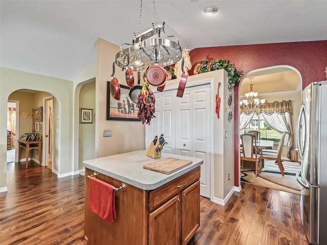 kitchen featuring arched walkways, vaulted ceiling, and freestanding refrigerator