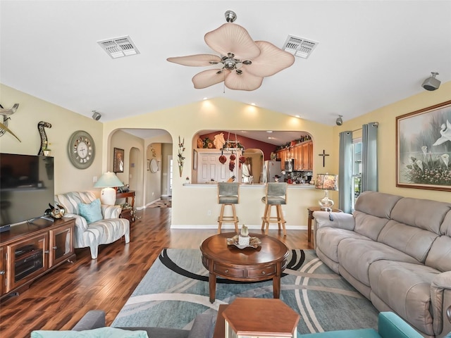 living area with vaulted ceiling, visible vents, arched walkways, and wood finished floors