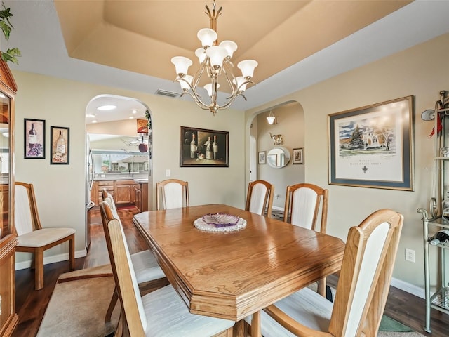 dining area with arched walkways, dark wood finished floors, and visible vents