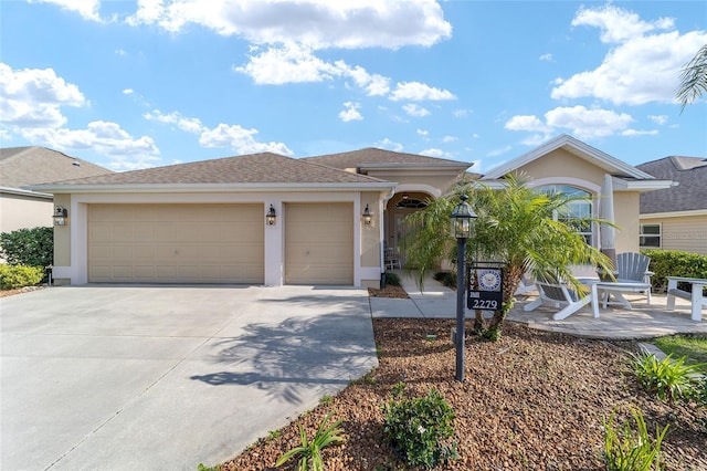 view of front of property featuring concrete driveway, an attached garage, and stucco siding