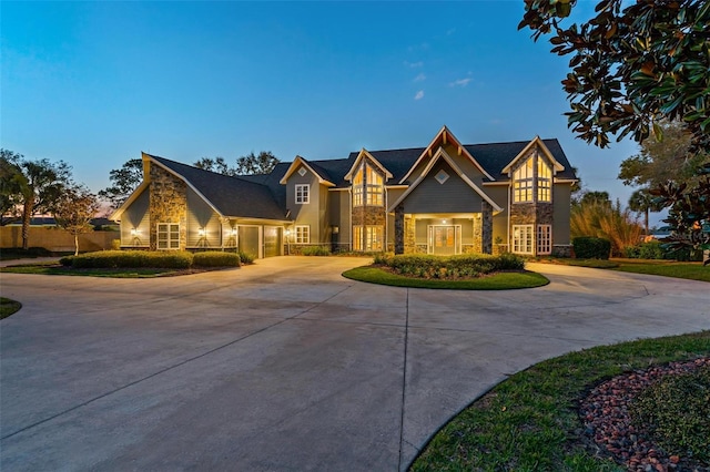 view of front of home featuring a garage, stone siding, and curved driveway