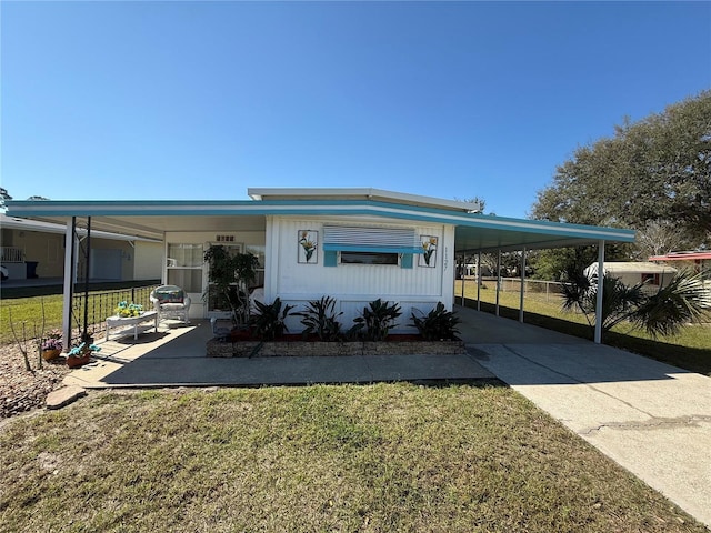 manufactured / mobile home featuring a carport, concrete driveway, and a front yard