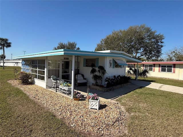 back of property with a yard and a sunroom