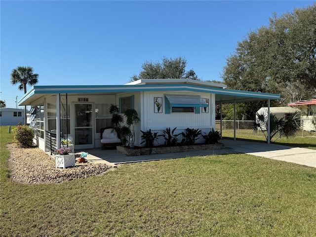 manufactured / mobile home with a carport, driveway, a front lawn, and a sunroom