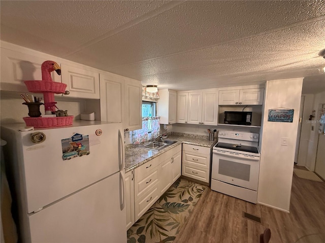 kitchen with dark wood finished floors, white cabinets, a sink, a textured ceiling, and white appliances