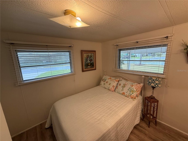 bedroom featuring multiple windows, a textured ceiling, and wood finished floors