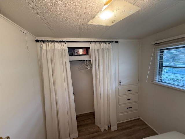 unfurnished bedroom with dark wood-style floors, a closet, and a textured ceiling