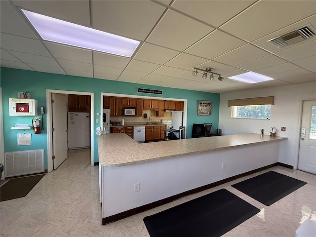 kitchen featuring a peninsula, white appliances, visible vents, and light countertops