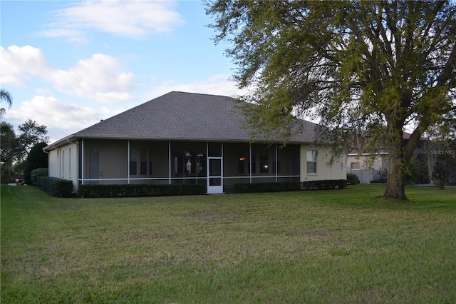 rear view of property featuring stucco siding, a lawn, a sunroom, and roof with shingles