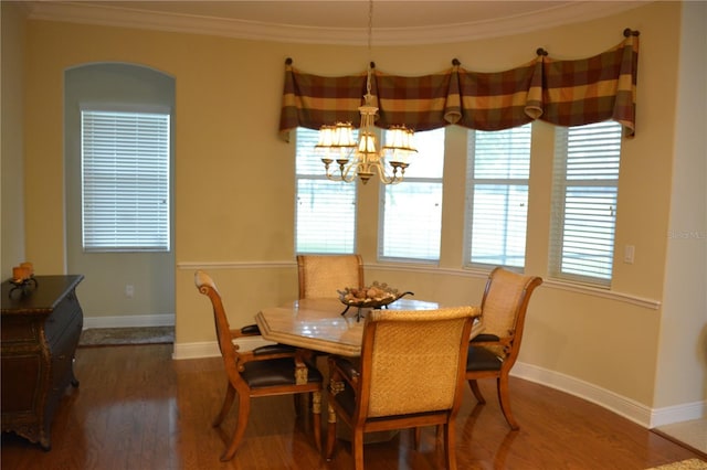 dining space featuring a chandelier, plenty of natural light, wood finished floors, and ornamental molding