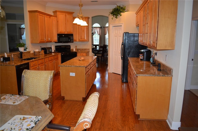 kitchen featuring black appliances, ornamental molding, a kitchen island, wood finished floors, and light stone countertops