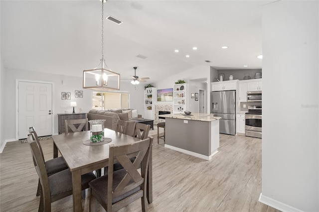 dining area with lofted ceiling, light wood-style flooring, a fireplace, and visible vents