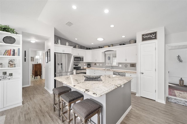 kitchen with white cabinetry, vaulted ceiling, a breakfast bar area, and stainless steel appliances