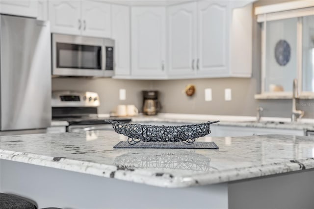 kitchen with appliances with stainless steel finishes, white cabinets, and a sink