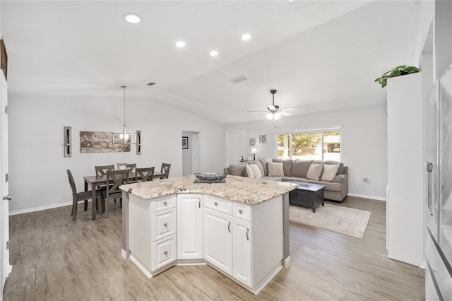 kitchen with a center island, vaulted ceiling, light wood-type flooring, white cabinetry, and pendant lighting