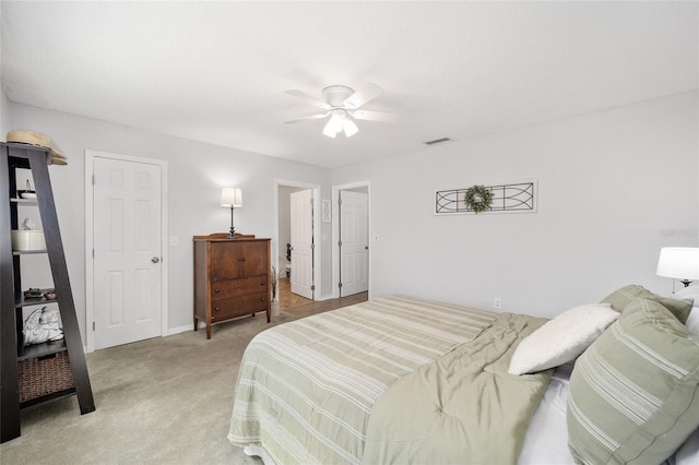 bedroom with a ceiling fan, visible vents, and light colored carpet