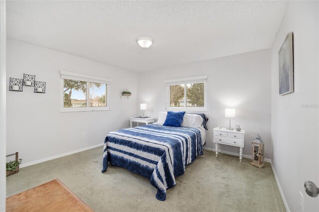 carpeted bedroom featuring a textured ceiling and baseboards