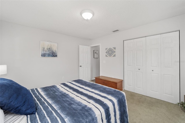 bedroom featuring carpet, a closet, visible vents, and a textured ceiling