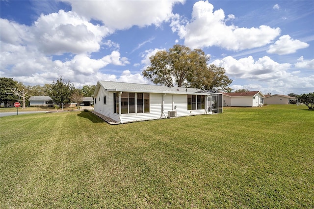 rear view of property featuring a sunroom, central AC, and a lawn