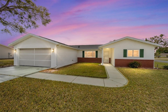 ranch-style home with a garage, concrete driveway, brick siding, and a yard