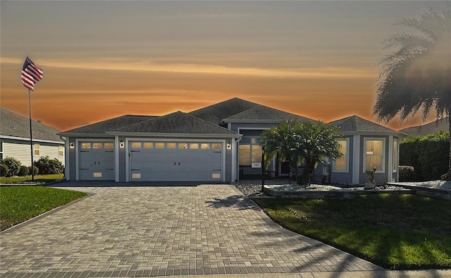 view of front facade featuring a garage, a front lawn, and decorative driveway