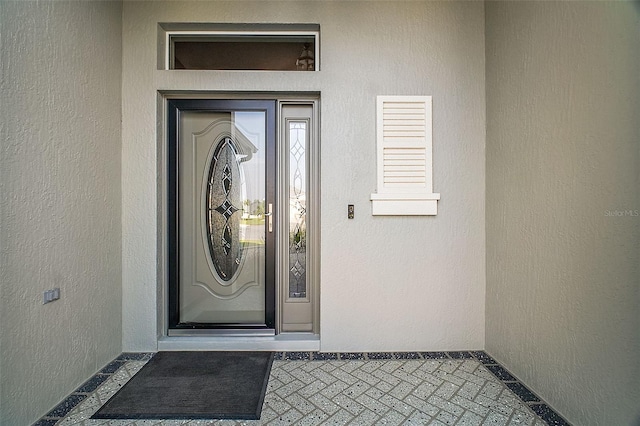 doorway to property featuring stucco siding