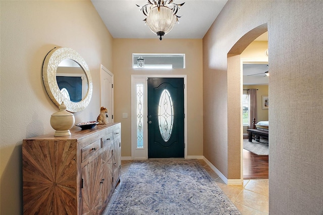 entrance foyer with light tile patterned floors, arched walkways, and baseboards