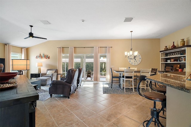 living area featuring lofted ceiling, visible vents, light tile patterned flooring, and ceiling fan with notable chandelier