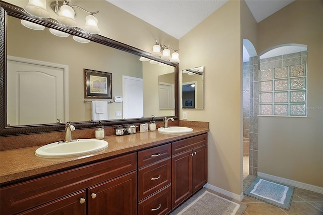 full bath featuring tile patterned flooring, a sink, baseboards, and a walk in shower