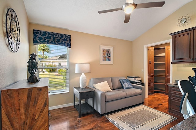 living room featuring dark wood-style floors, vaulted ceiling, baseboards, and ceiling fan