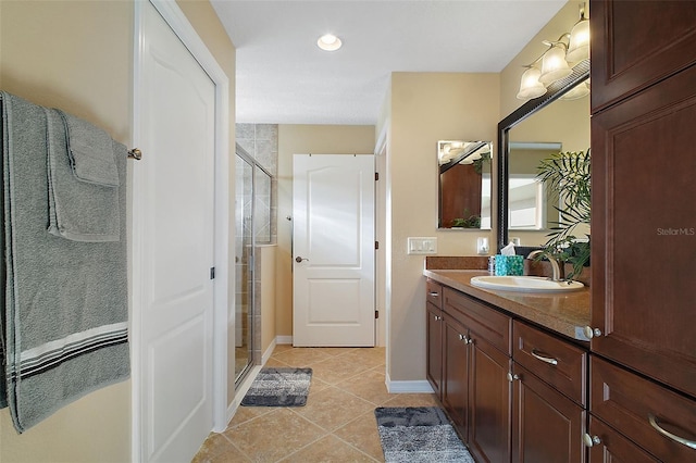 bathroom featuring a shower stall, baseboards, tile patterned flooring, and vanity