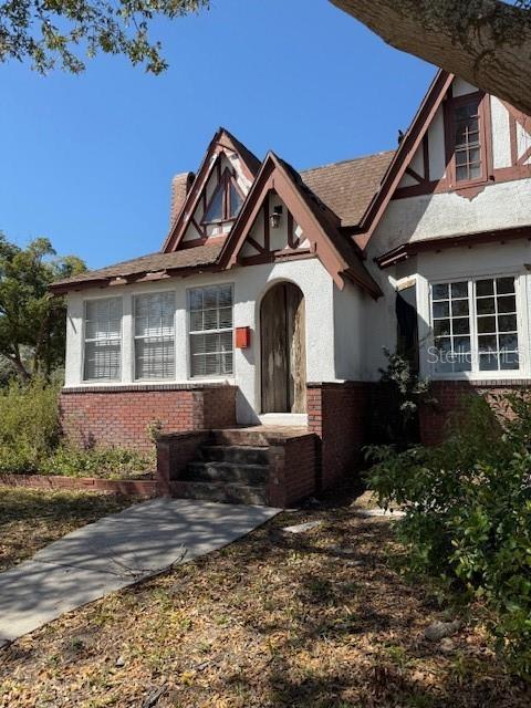 english style home with brick siding and a chimney