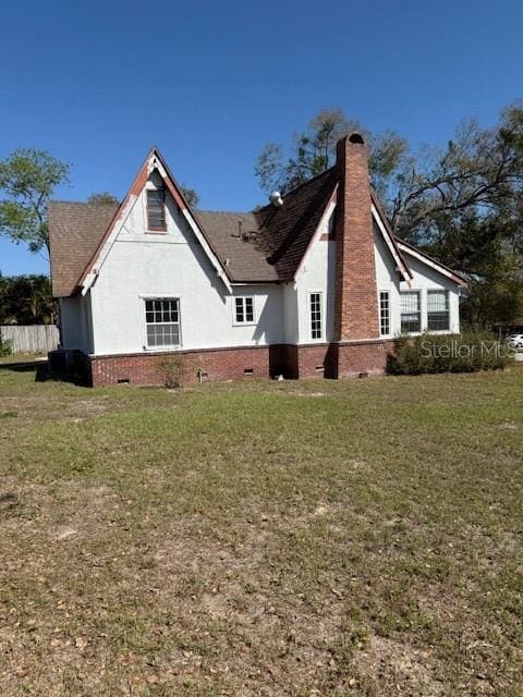 view of property exterior featuring crawl space, a yard, a chimney, and stucco siding