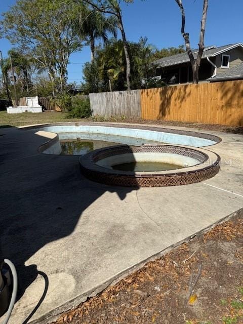 view of swimming pool with a pool with connected hot tub and fence