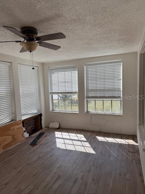 unfurnished room featuring a textured ceiling, a ceiling fan, and wood finished floors