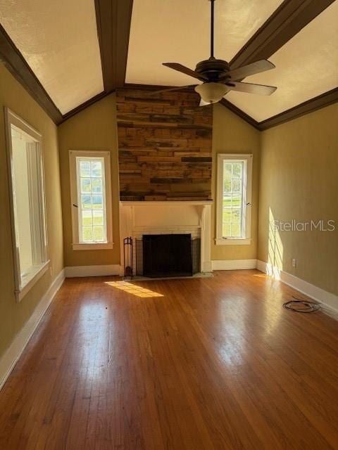 unfurnished living room featuring ceiling fan, a fireplace with flush hearth, wood finished floors, vaulted ceiling, and crown molding