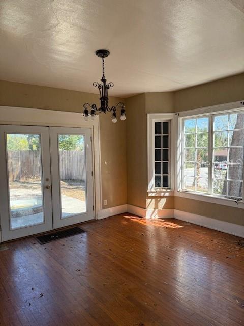 interior space featuring wood-type flooring, baseboards, a notable chandelier, and french doors