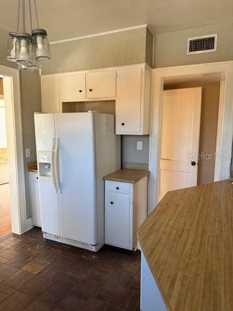 kitchen with white refrigerator with ice dispenser, decorative light fixtures, visible vents, an inviting chandelier, and white cabinetry