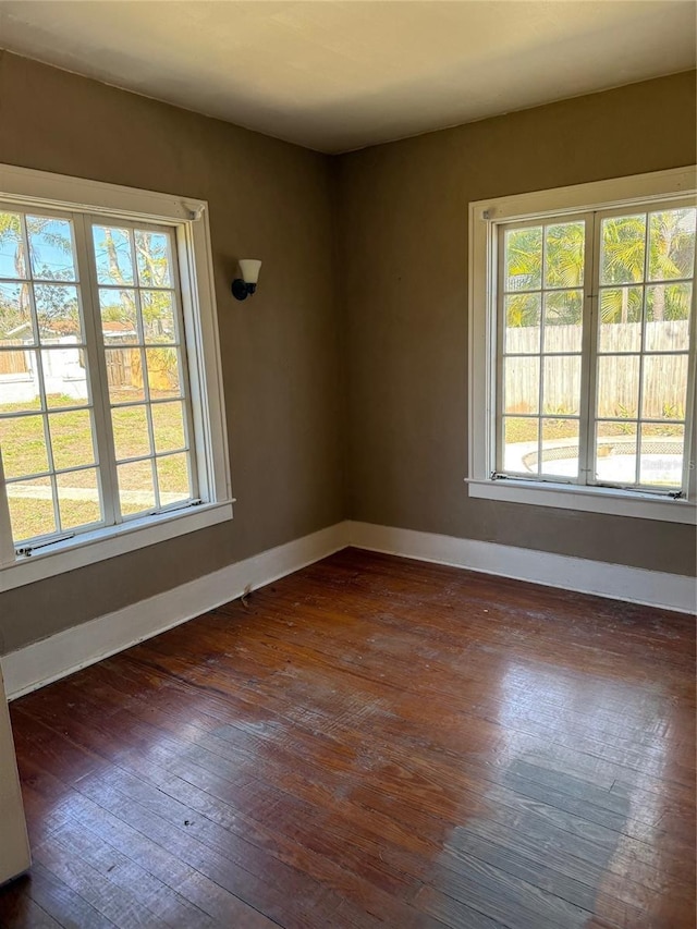 spare room featuring dark wood-style floors and baseboards