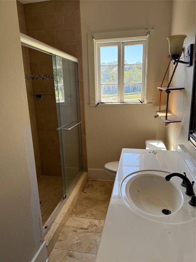 bathroom featuring toilet, a stall shower, baseboards, and vanity