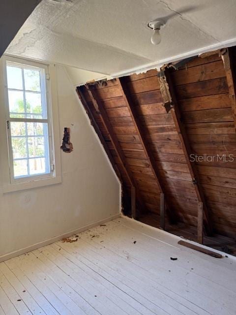 interior space featuring wood-type flooring, baseboards, and vaulted ceiling