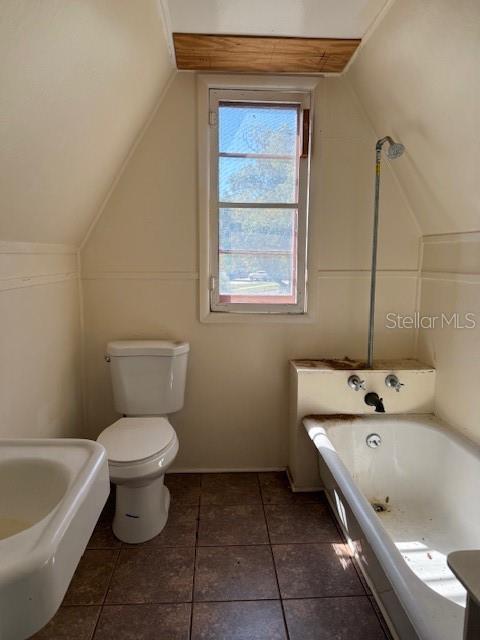 bathroom featuring lofted ceiling, toilet, and a bath