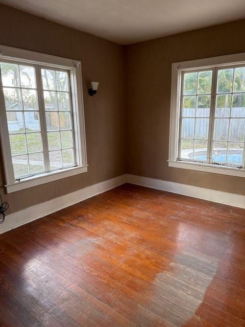 spare room featuring baseboards and hardwood / wood-style flooring