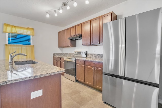 kitchen featuring stainless steel appliances, brown cabinetry, a sink, and under cabinet range hood