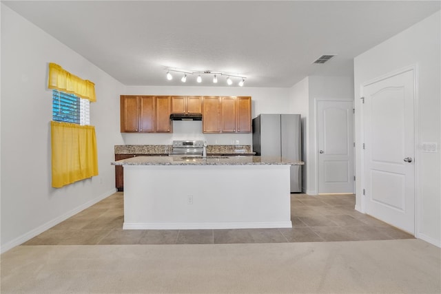 kitchen featuring light stone counters, a sink, visible vents, appliances with stainless steel finishes, and an island with sink