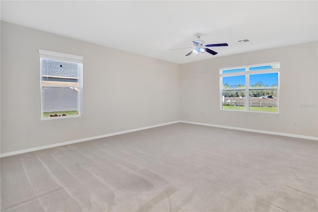 spare room with ceiling fan, visible vents, baseboards, and light colored carpet