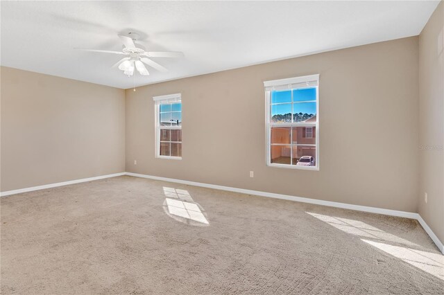 carpeted spare room with baseboards and a ceiling fan